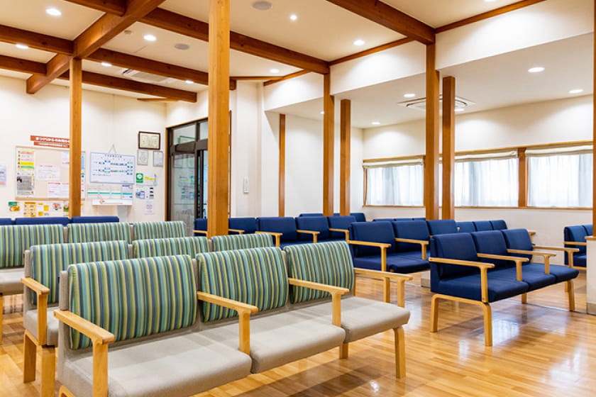 3席分が連なるそれぞれ緑と青の背もたれの椅子が並ぶ待合室