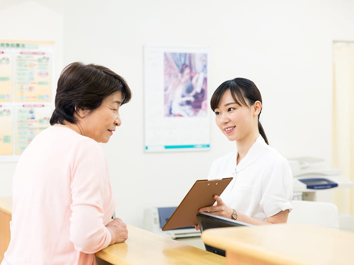 女性患者に受付の女性が笑顔で対応している