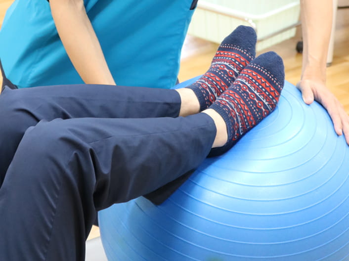 理学療法士とバランスボールを使ってリハビリを行っている